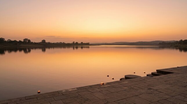 Peaceful river landscape at sunset with small floating lamps near a stone step platform