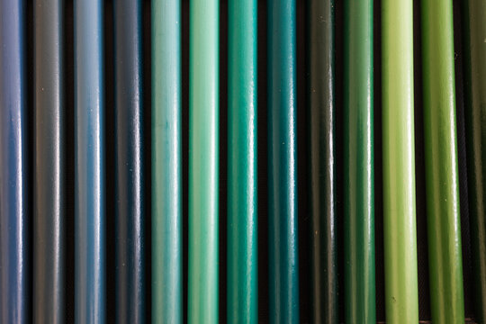 close-up of blue turquoise and green colored pencils neatly lined up in pencil case, concept of creativity, drawing, education and art supplies