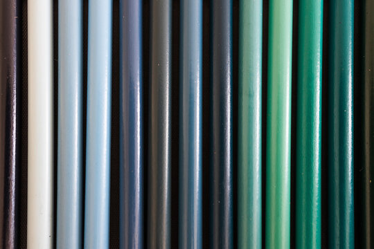 close-up of blue turquoise and green colored pencils neatly lined up in pencil case, concept of creativity, drawing, education and art supplies