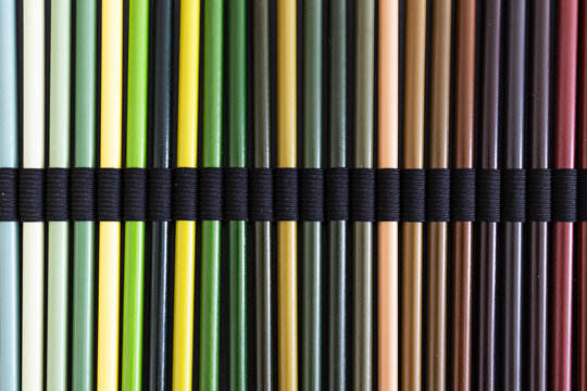 close-up of green and brown colored pencils neatly lined up in pencil case, concept of creativity, drawing, education and art supplies
