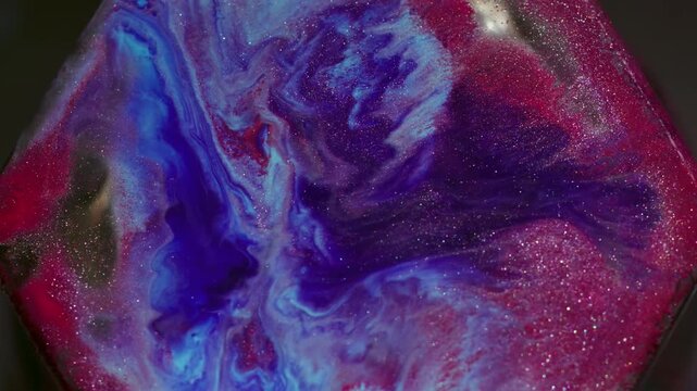 Spatter liquid. Fluid spill. Defocused purple blue red color glitter gem paint particles sparking rhombus floating on abstract background.