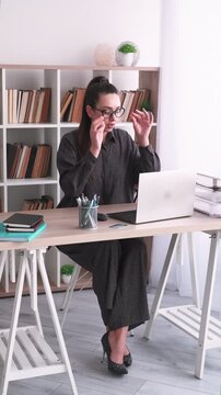 Vertical video. Professional workflow. Office worker. Disciplined business woman typing information using laptop at desk at workplace indoor.