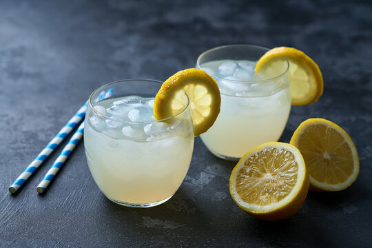 Freshly made lemonade with ice on dark table, selective focus, cold refreshing drink in summer .
