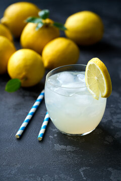 Lemonade with fresh lemon in glasses on dark background. Cold refreshing lemonade for summer party and fun.