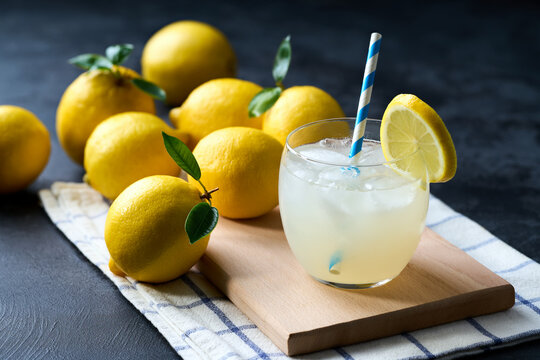 Traditional homemade lemonade in glass with ice on a black table, selective focus. Cold refreshing lemonade .