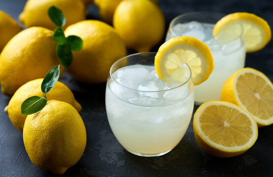 lemonade water with lemon slices , healthy and detox water drink with ice in summer on the dark kitchen table.