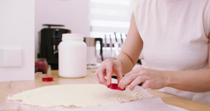 Preparing cookies. Cutting dough. Woman baker hand making homemade meal tasty treat with star shape cutters at light modern kitchen.