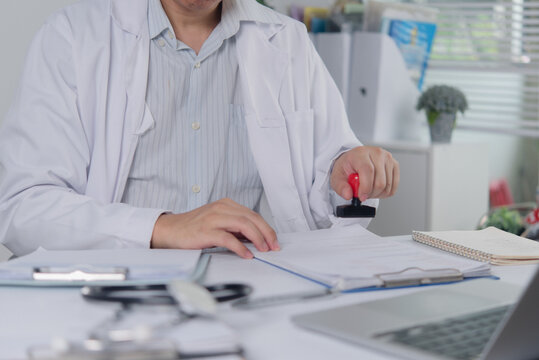 Doctor hand stamping medical document on desk for healthcare approval and certification