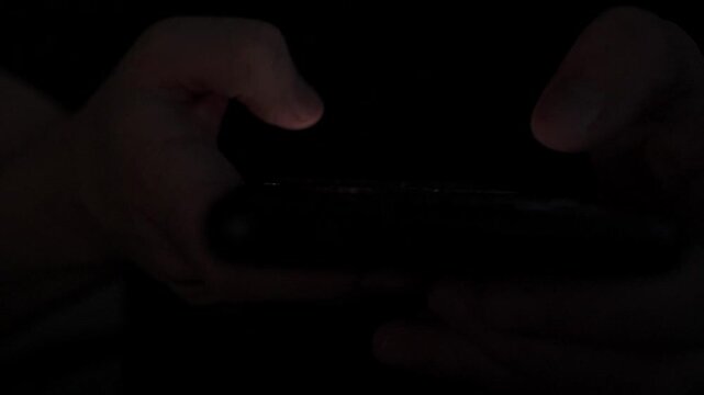 Close Up of Man Scrolling Social Media on Smartphone in Dark Room at Night