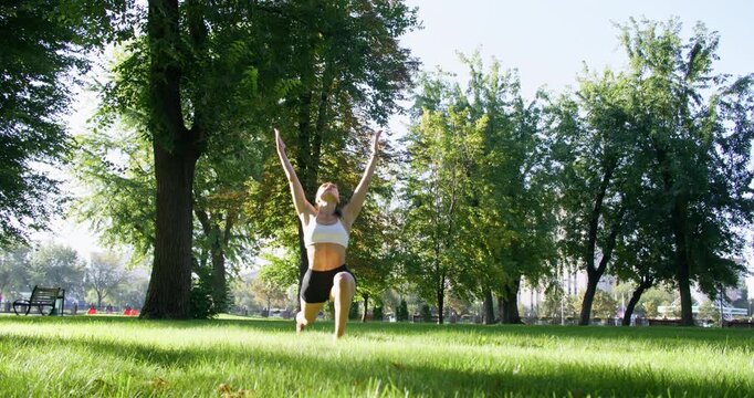 Healthy lifestyle. Outdoor yoga. Slim athletic female performing active sportive training in natural light green summer park.
