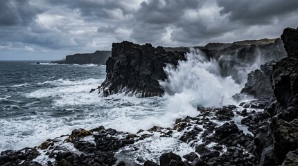 Fototapeta premium Dramatic ocean waves crashing against dark volcanic rocks under a moody stormy sky on a rugged coastal landscape.