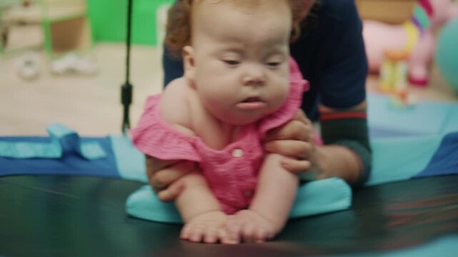 Baby with Down syndrome performing physical therapy exercises, developing motor skills, and receiving early intervention in a therapy swing
