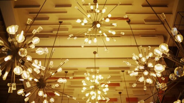 Low angle view of modern starburst sputnik chandeliers hanging from decorative ceiling in luxury interior design setting.
