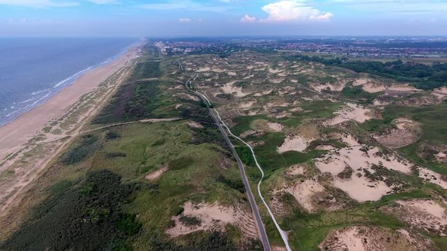 High angle horizontal aerial drone video clip of cycling path, walking trails, sand dunes, North Sea coast, and distant Katwijk aan Zee skyline in Meijendel, Wassenaar, Netherlands, West Europe