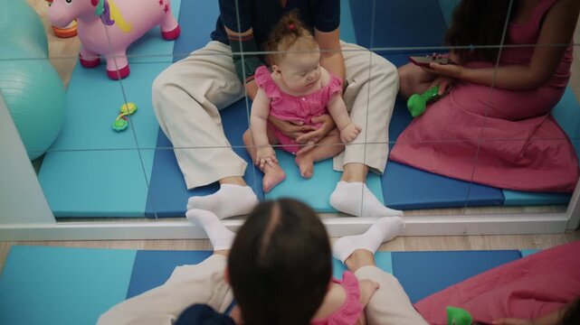 Baby girl getting physical therapy, developing motor skills, and receiving rehabilitation in a child friendly center with a professional
