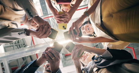 Obraz premium Below, phone and group of business people in circle with connection, online and social media post. Happy men, women and technology in office for community, ux survey or feedback for company policy