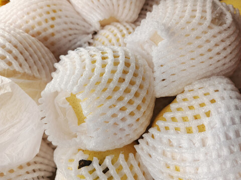 Fresh pears wrapped in white protective foam net bags background