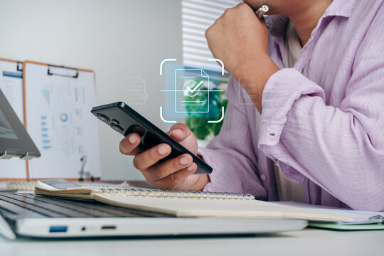 Business professional using mobile phone to scan document with holographic OCR scanner interface icon on desk, concept of optical character recognition, digital data extraction, and paperless office.