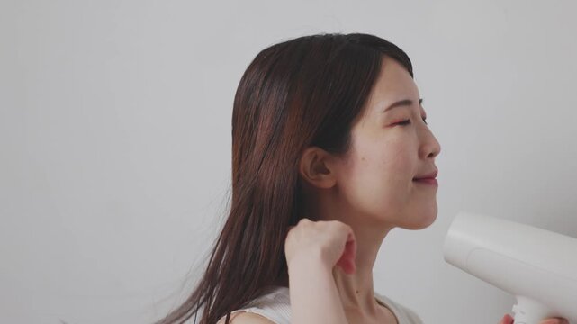 ドライヤーを使いながら手ぐしで髪を乾かす女性