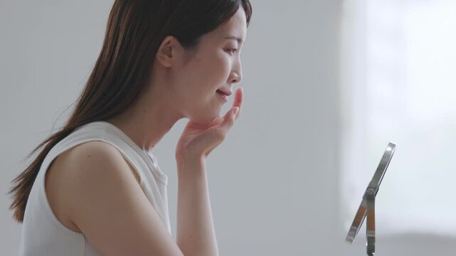 卓上鏡で顔の肌を丁寧に確認する笑顔の女性