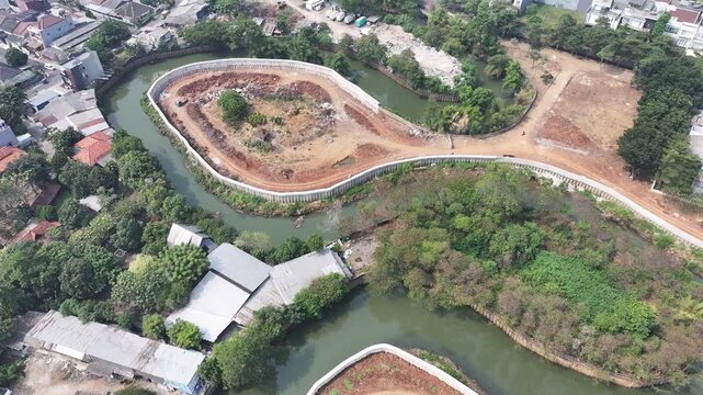 Aerial view of urban development with curved river, construction site, and residential housing Drone perspective of a developing cityscape featuring a winding river, earthworks, and scattered building