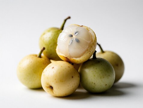 Pile of duku fruits with one split open showing translucent pulp and seeds. Tropical produce presented on clean white backdrop for healthy eating themes.
