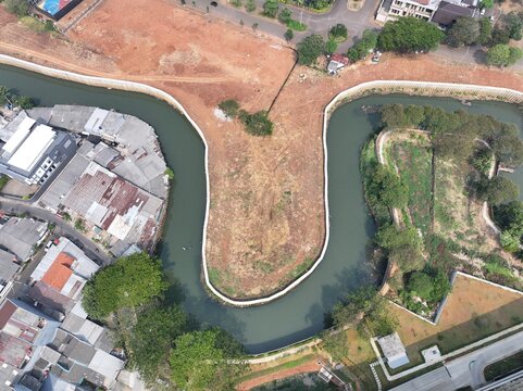 Aerial view of urban development with curved river, construction site, and residential housing Drone perspective of a developing cityscape featuring a winding river, earthworks, and scattered building
