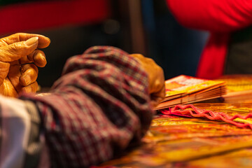 Obraz premium Taipei, Taipei City/Taiwan - 02/04/2026: Hands and coin scratching an instant lottery ticket under warm market light.