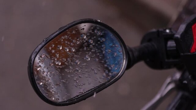 Close up of a motorcycle side mirror covered in raindrops