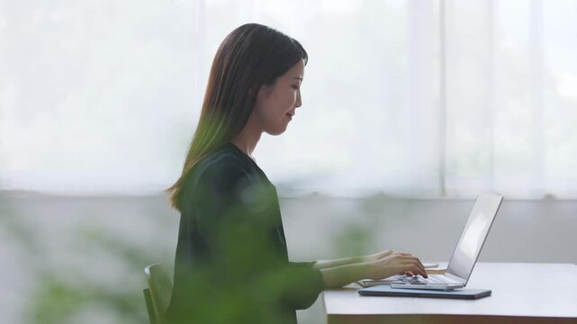 ノートパソコンで仕事をする女性の横顔