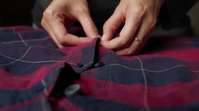 folding and smoothing a plaid shirt on an ironing board