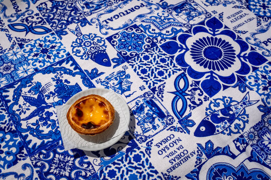Wide shot of pastel de nata custard tart on blue tablecloth with