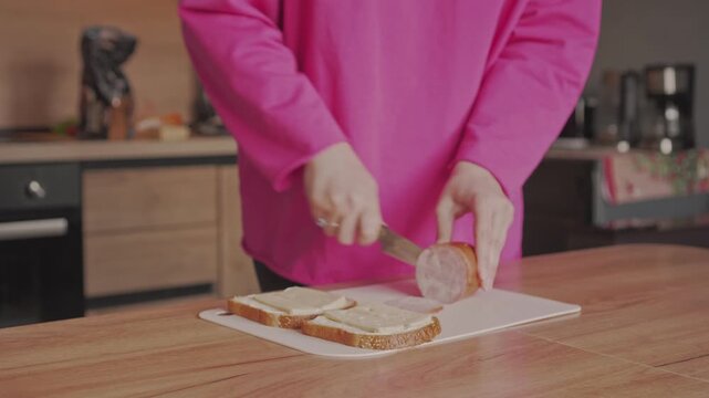 A housewife slices ham to make sandwiches. Cooking breakfast at home.