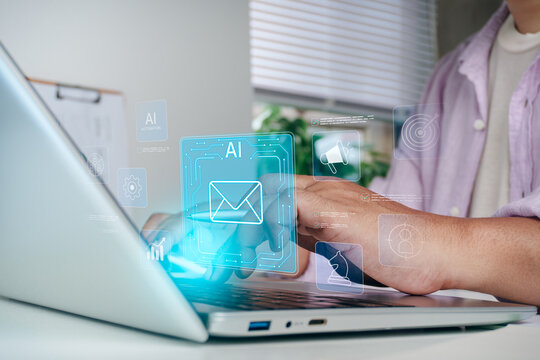 Business professional typing on laptop keyboard with holographic AI artificial intelligence and email communication icons, concept of smart automated messaging, digital marketing, and tech innovation.