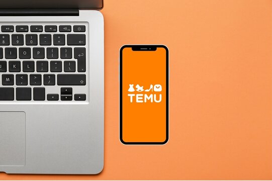 TEMU logo on mobile phone screen on desk with laptop. Chinese e-commerce online marketplace. 10-JULY-2026-ADANA-TURKEY