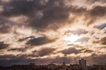 Fototapeta premium Cloudy skyline dances with sunlight in a cityscape view during sunset