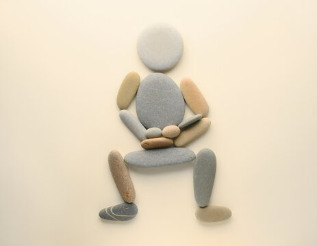Figurative Stone Art, Human Silhouette Formed by Smooth Pebbles, Zen Meditation Pose, Natural Elements Composition, Serene Balance Concept, Minimalist Organic Sculpture