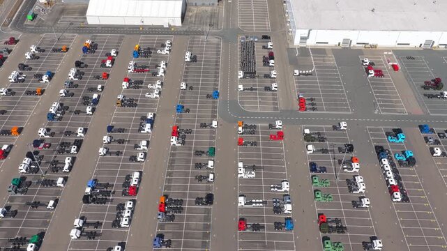 Huge parking lot at a truck manufacturing factory with rows of newly built vehicles and chassis waiting for distribution and delivery