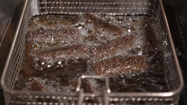 Close-up of sliced black bread, fried in boiling oil, deep-fried in a restaurant kitchen. Snacks are made at the bar, fast food, a beer plate.