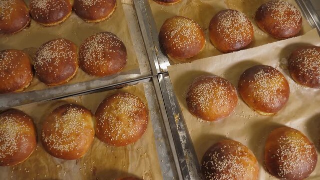 Close-up of freshly baked burger buns with sesame seeds in the restaurant kitchen. Freshly baked burger buns have a crispy crust.
