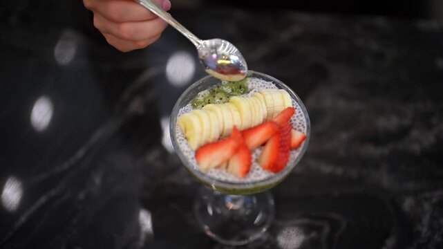 Healthy chia pudding bowl topped with fresh sliced banana kiwi and strawberry fruit pieces.