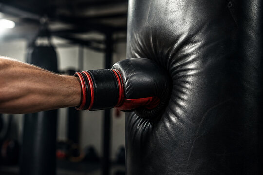 Boxing glove impacting a heavy bag with visible indentation, motion capture in a gym.