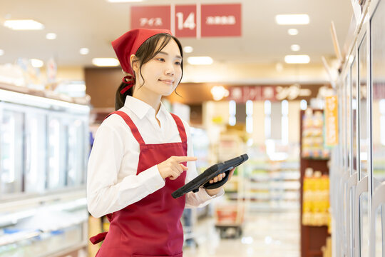 スーパーの冷蔵売り場でタブレットを使い商品管理をする女性店員