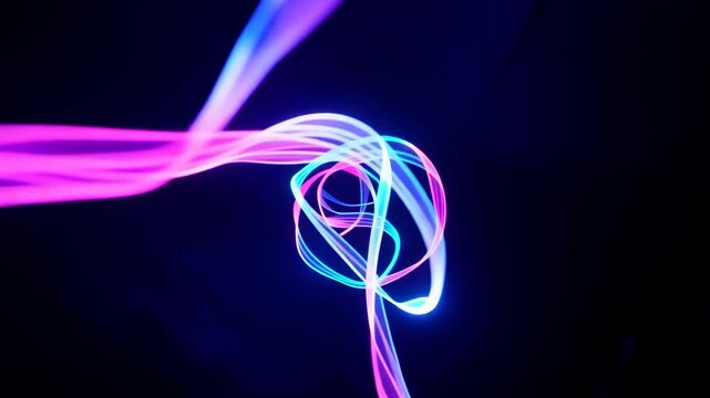 Colorful light trails intertwine and flow in a dynamic sequence, showcasing vibrant blue and pink hues against a dark background in a mesmerizing visual display