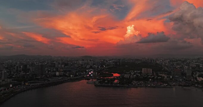 Beautiful sunset view of Mumbai, Maharashtra, with a dramatic orange sky illuminating the city skyline and calm waterfront. The glowing clouds, shimmering water, and striking evening cityscape.