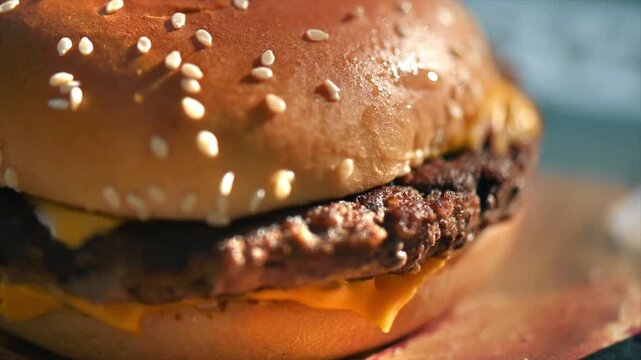 Freshly cooked cheeseburger with melted cheese and sesame bun close up shot.