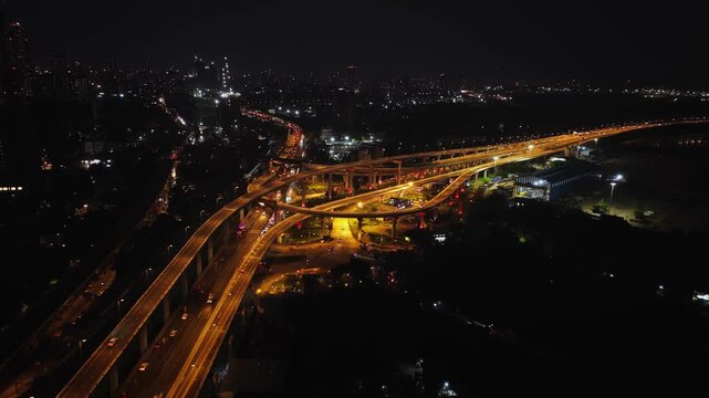 A stunning aerial night view of Atal Setu (Mumbai Trans Harbour Link), showcasing the intricate network of illuminated flyovers and highways glowing in golden light.