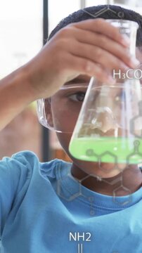 Conducting chemistry experiment, child holding flask with chemical formulas over