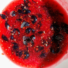 Vibrant red berry sauce with dark fruit pieces © schankz