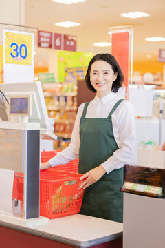 スーパーのレジで笑顔で接客する女性店員